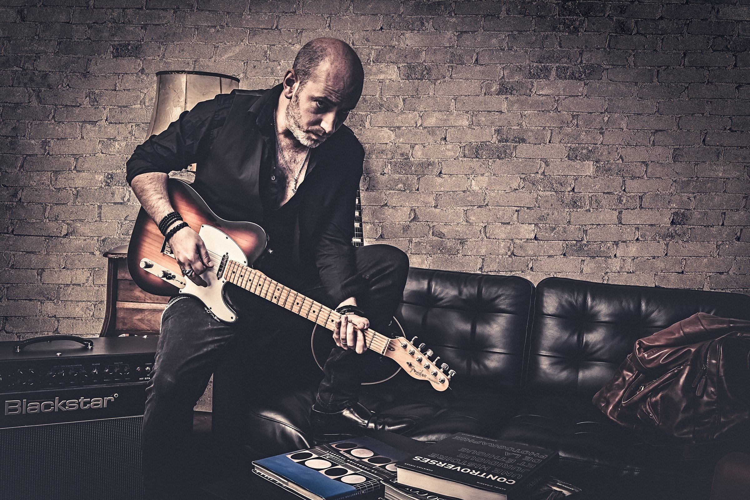 Quentin Piepszownik penché sur une guitare électrique sunburst.